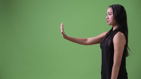 profile view of young beautiful asian businesswoman with stop gesture