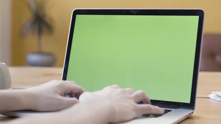 Person arbeitet am Laptop mit Greenscreen