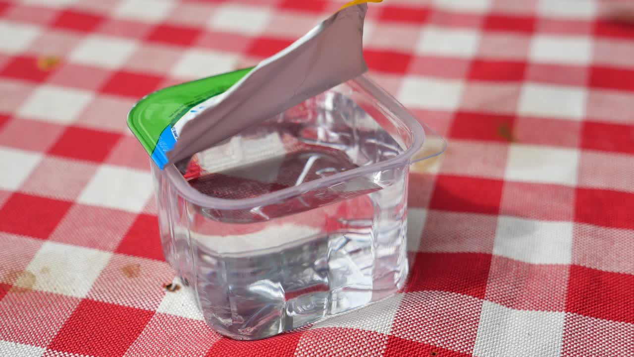 체커 된 식탁 천 에 물 을 담은 플라스틱 컵