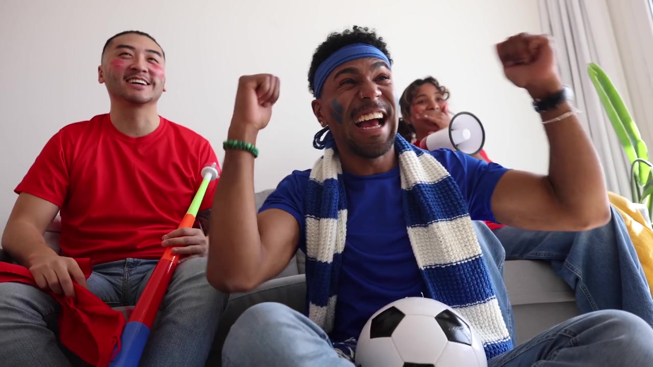 Grupo de amigos animando un partido de fútbol en casa