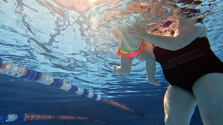 madre enseñando al bebé a nadar bajo el agua