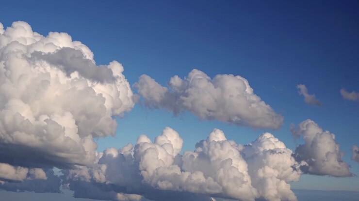 Ein ruhiges Video von flauschigen weißen Wolken vor einem tiefblauen Himmel, aus der Froschperspektive aufgenommen.