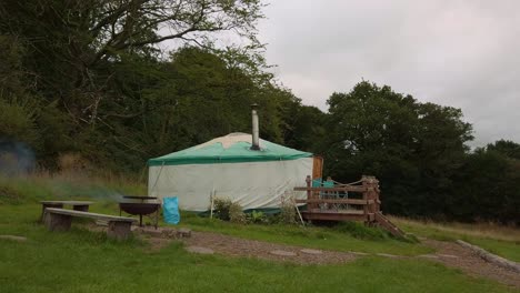 yurt camping in woodland while a bbq burns