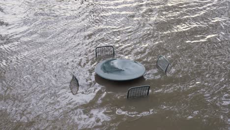 heavy flood from river submerging outdoor table and chairs - from alternate angle