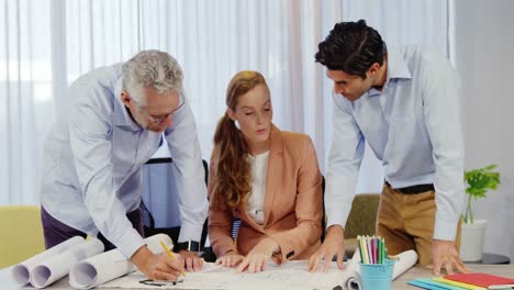 Businesswoman-and-coworkers-discussing-blueprint