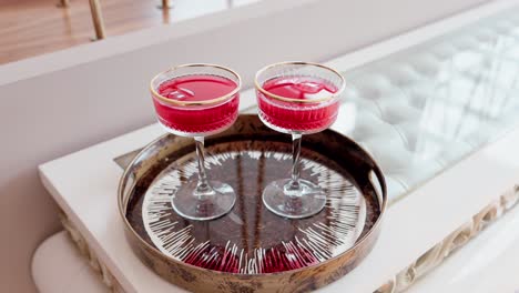 elegant red drinks in coupe glasses served on modern decorative tray