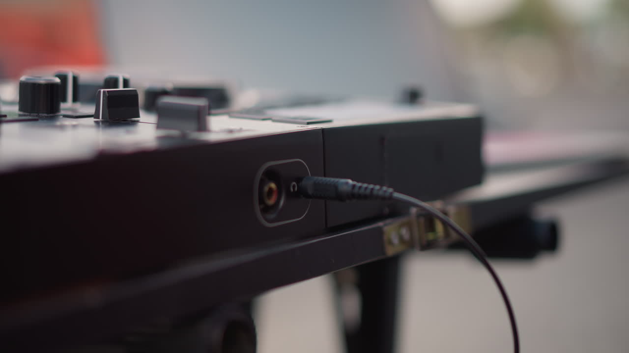 closeup plugged cable resting on mixer evening bokeh stationary shot shows secured jack in input port with soft city lights and shallow focus, calm mood sound technician prepares gear, quiet