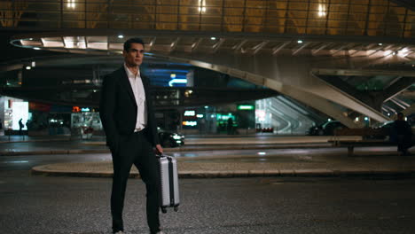 business man carrying luggage walking evening street. elegant guy crossing night