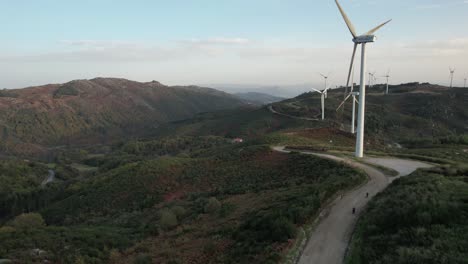 Drohne-Folgt-Zwei-Moto-Reisenden,-Die-Auf-Der-Windmühlenstraße-Mit-Berglandschaft-Fahren