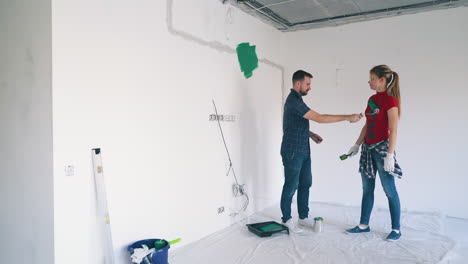 positive man and girl paint each other at white wall in room