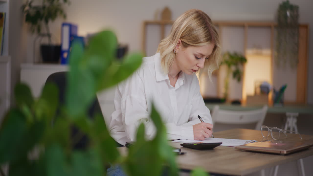 Kvinde tæller regninger og husholdningsudgifter på lommeregner om aftenen.
