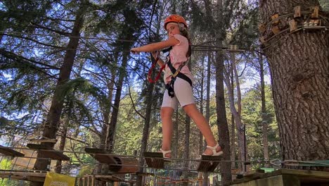 adventurous girl child cross suspended bridge at kids rope adventure park