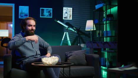 overjoyed man sitting on couch laughing while watching funny comedy movie