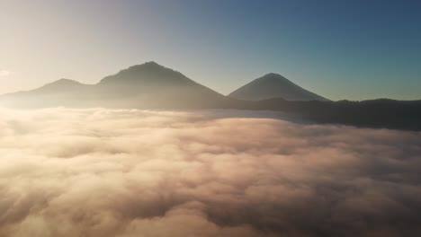 aerial view over valley covered in fog with mountain background, sunrise in bali, indonesia