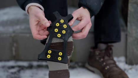 hands putting ice spikes on slippery shoes for better grip on ice, close up