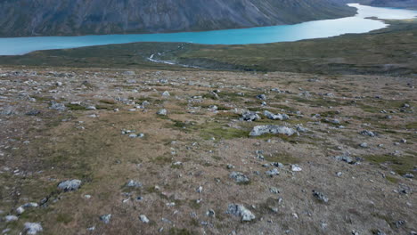 toma aérea amplia de personas caminando por un sendero de montaña, cumbre de senderismo, vista de pájaro inclinada hacia el horizonte