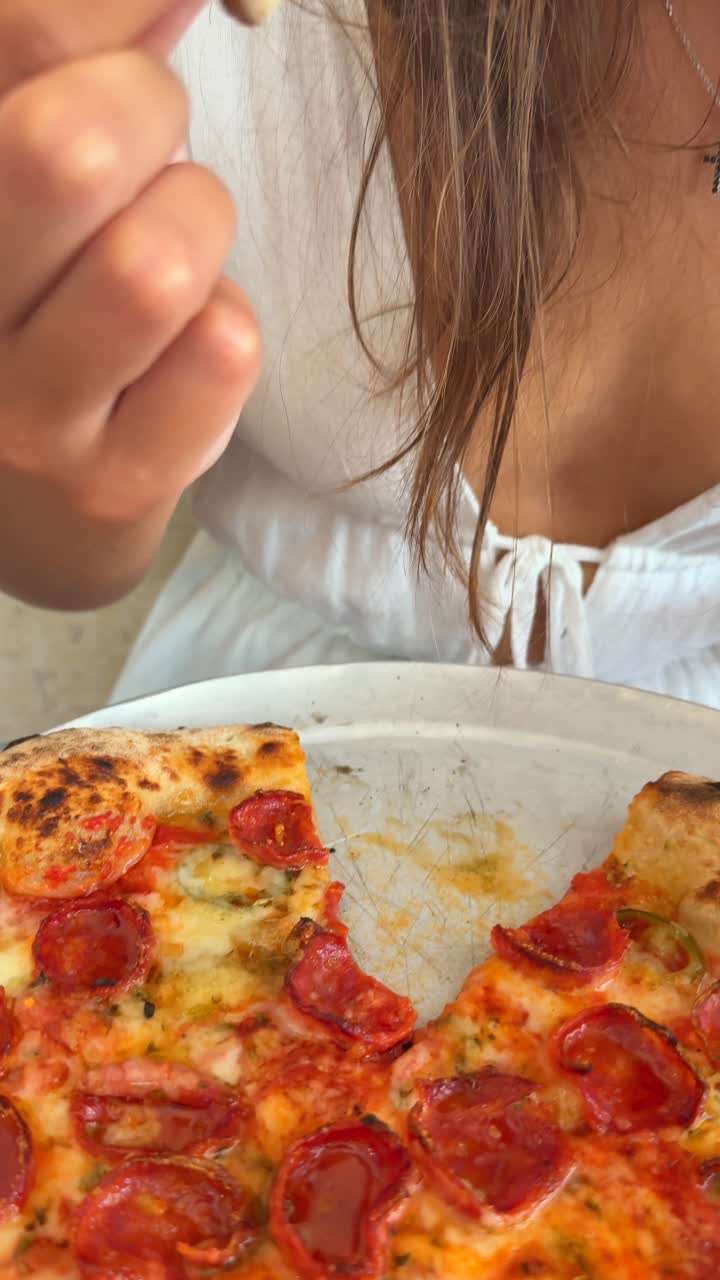 Person eating a slice of pepperoni pizza