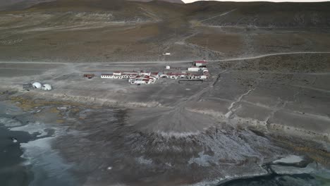 Aerial-of-eco-lodge-in-the-deserted-landscape-of-Salar-de-Uyuni-close-to-Uyuni-Salt-Lake-and-at-the-foot-of-the-Thunupa-volcano,-Bolivia,-Mexico,-USA