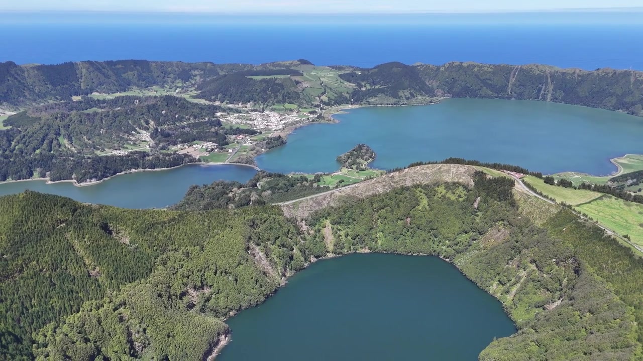 アゾレス諸島サンミゲル島セテ・シダーデスにある緑と青の湖の息をのむような空撮パノラマ。ポルトガル諸島の火山カルデラ、豊かな森、急峻な尾根上空をドローンが飛行する。