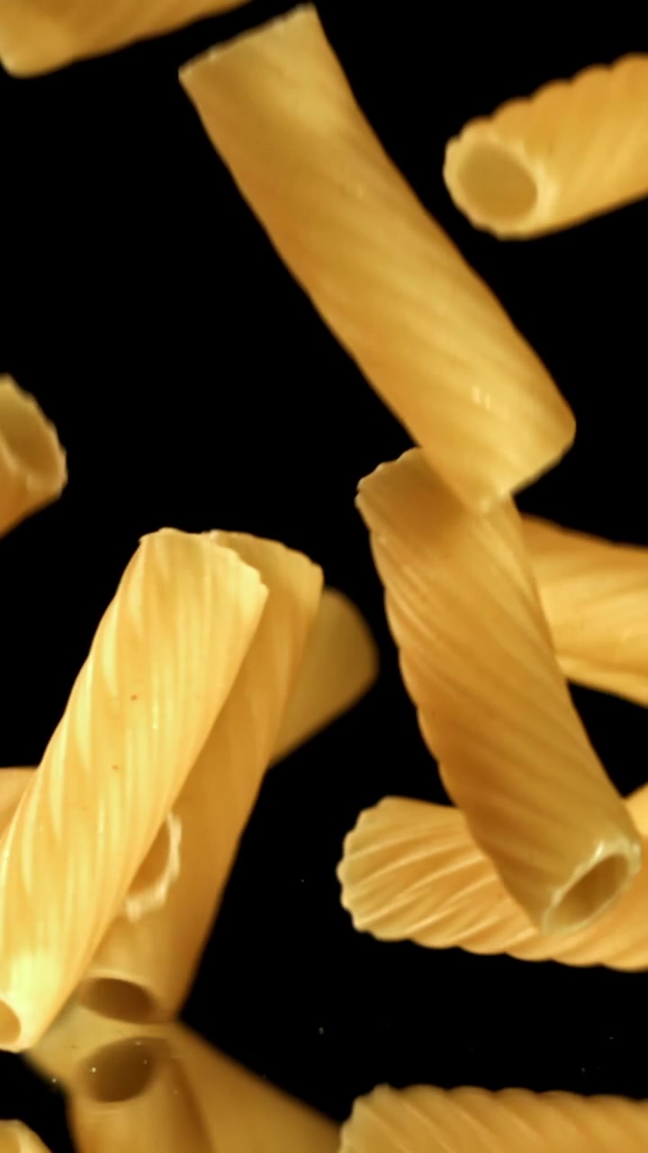 Rallentatore di pasta Rigatoni secca che cade su sfondo nero