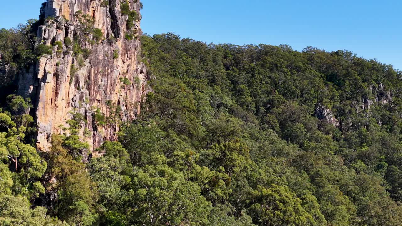 Aerial footage of Nimbin Rocks, showcasing lush greenery and rugged cliffs under bright daylight