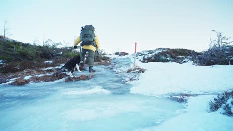 backpacker person climbing over icy landscape with his husky dog in trondheim, norway