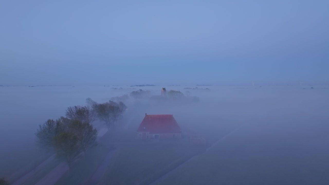 Ovenfra-perspektiv av tåkete nederlandske jorder, elv og landsbykapell ved daggry
