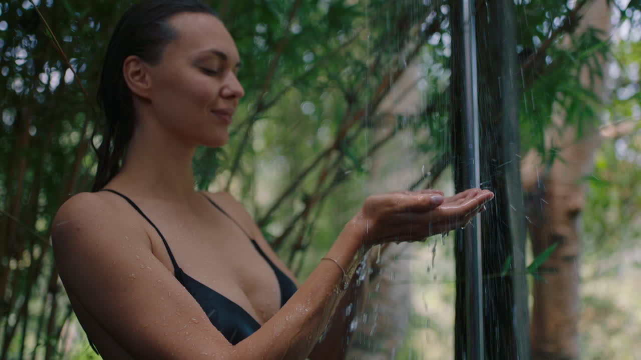 hermosa mujer en la ducha atrapando agua en las manos disfrutando de una limpieza refrescante duchándose al aire libre en la naturaleza