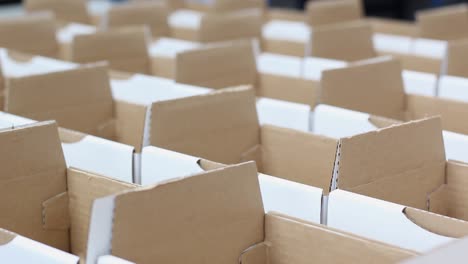 many rows of small white boxes sit in a packaging warehouse