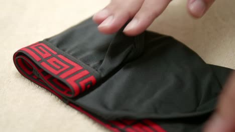 Hand-of-man-are-folding-the-men's-red-edge-and-black-color-underwear-in-order-to-facilitate-storage-in-travel