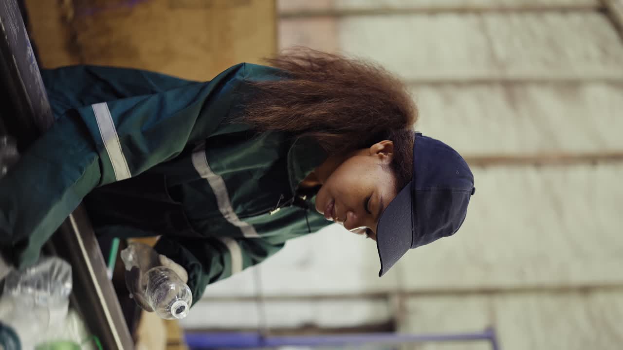 Afro american girl sorting bottles at a garbage recycling plant. Pollution control