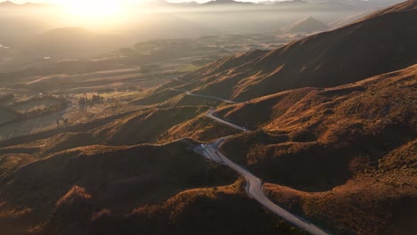 Road-trip-in-New-Zealand,-winding-road-and-beautiful-sunset-over-the-mountains