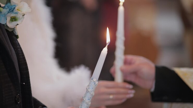 La sposa e lo sposo stanno in chiesa, tenendo candele tra le mani.