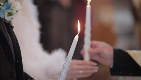 the bride and the groom stand in church, holding candles in their hands