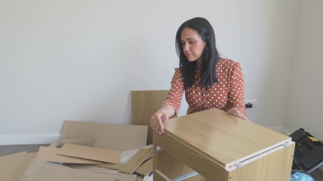 Donna che assembla un armadietto di mobili in kit a casa
