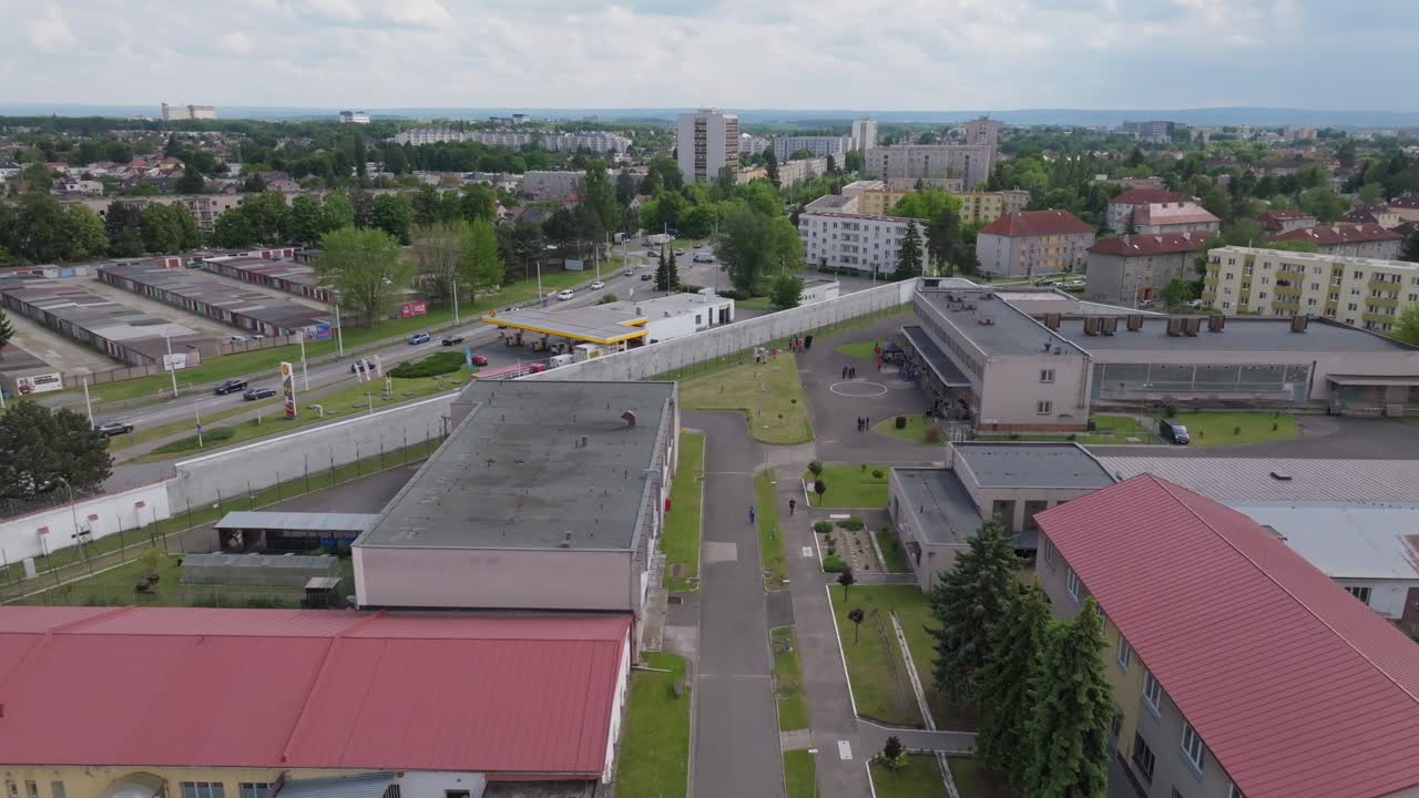 High aerial wide shot of secured prison facility with perimeter walls, guard towers, and barbed wire fences