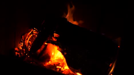 home log wood fire burning in slow motion with bright hot embers, ash and orange red flickering flames