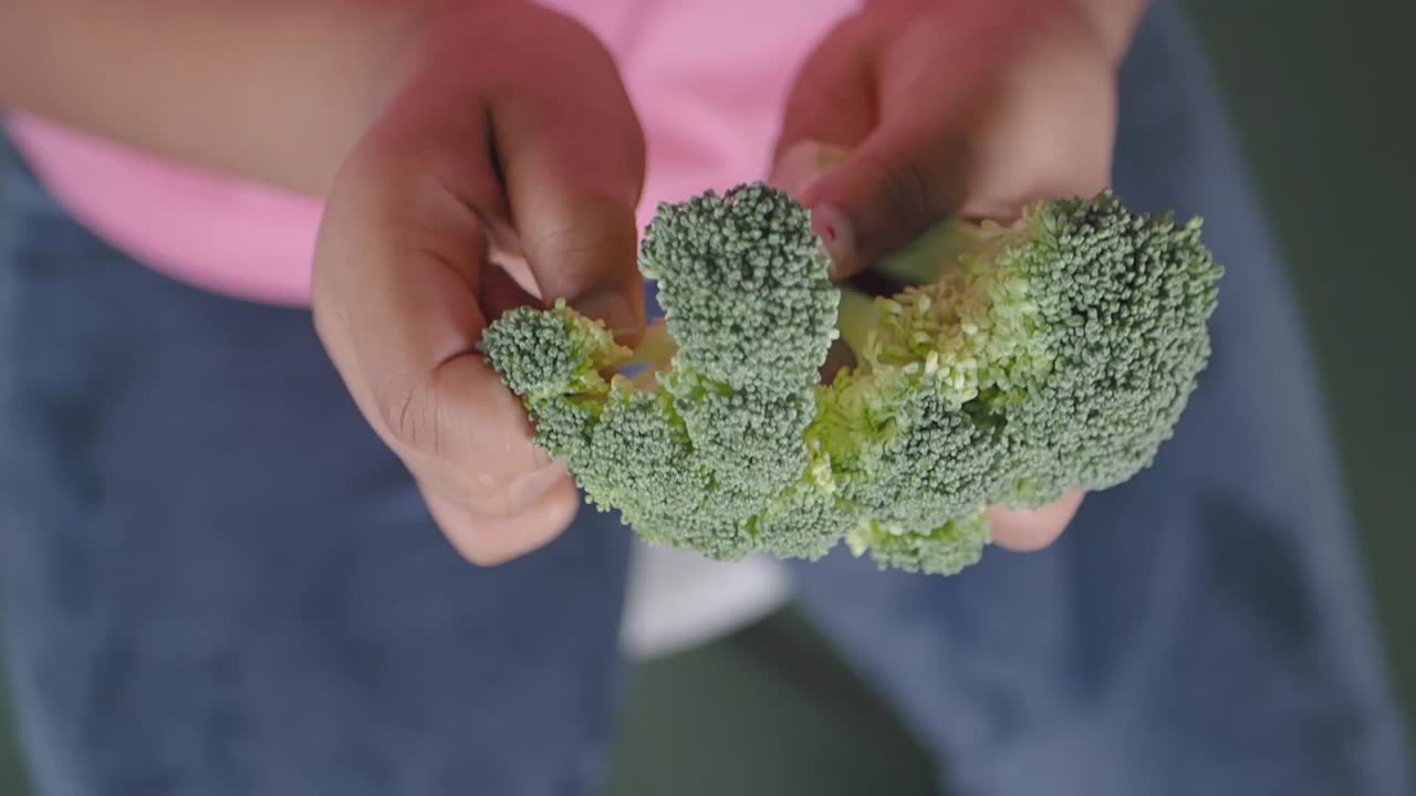 Primo piano di una persona che tiene in mano un broccolo