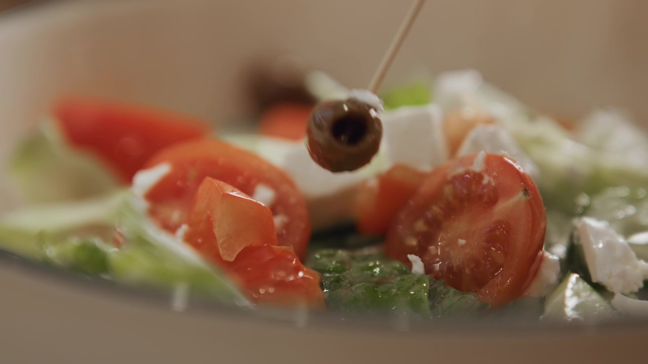 Close up of fresh salad ingredients including tomatoes olives and feta cheese as olive oil is drizzled over them. scene focuses on vibrant textures details like juicy tomato slices crumbled