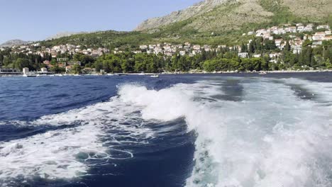 sunny summer day on the adriatic sea, with powerboat living white foam behind near dubrovnik, croatia