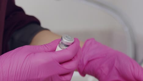 doctor or nurse's hands in latex gloves seen opening a vial or ampoule for botox treatment - isolated slow motion