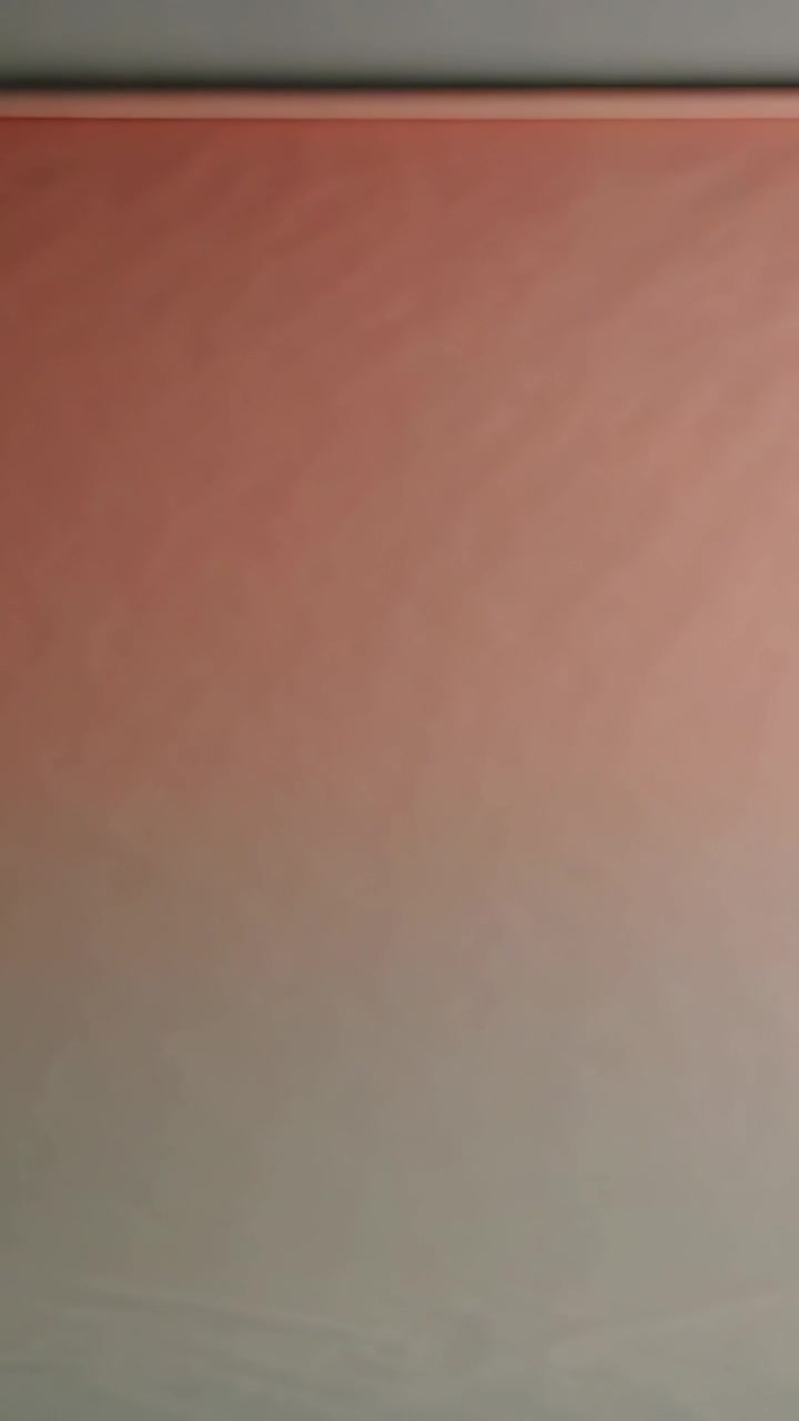 Vertical video: Shifting large panel moving from teal to red indoors as top trim light shifts