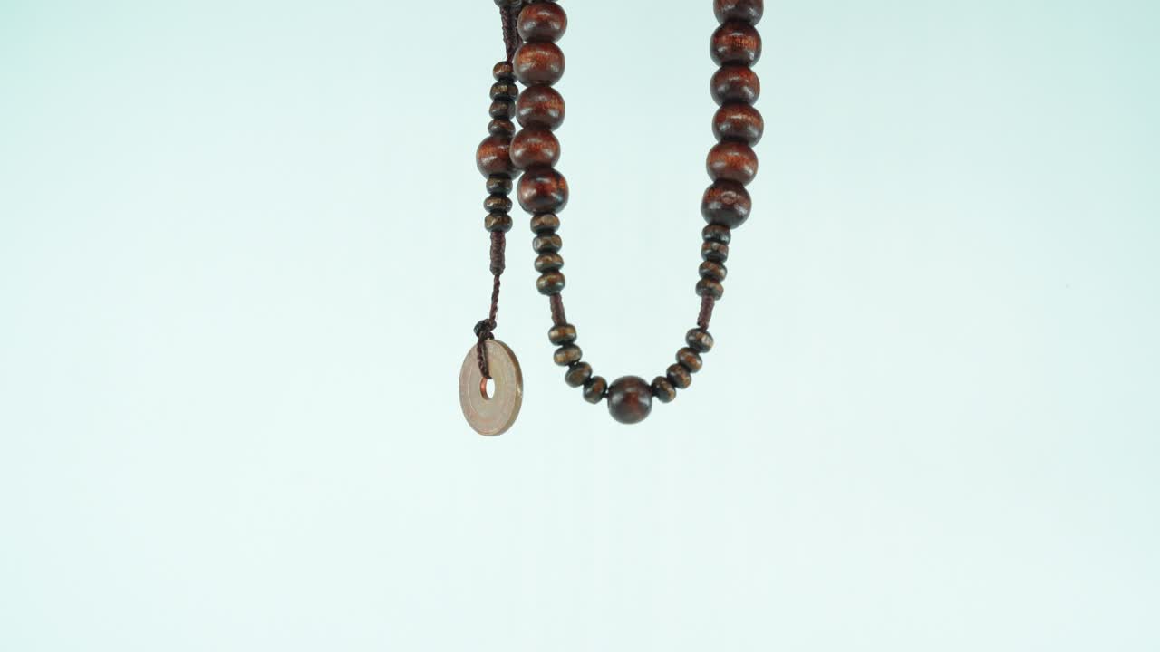 Un collier en bois avec une vieille pièce asiatique, plan macro en gros plan 4K, fond blanc.
