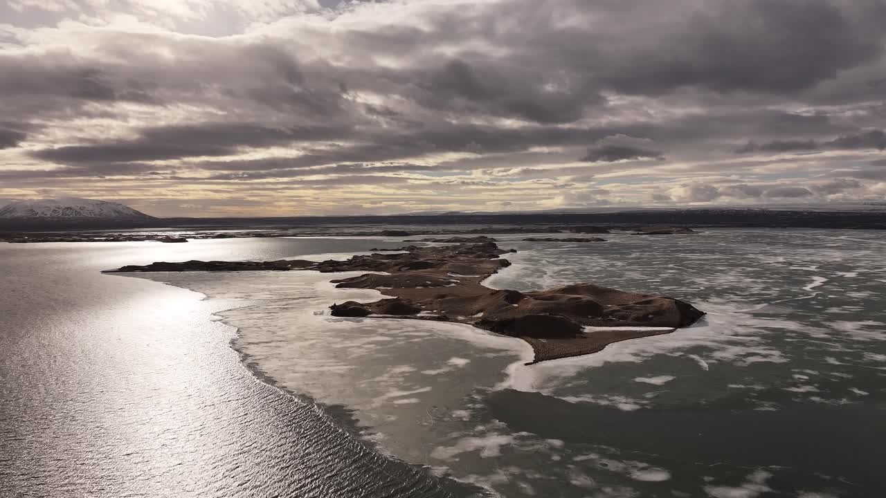 Dramatic sunset behind clouds over an ice-covered lake. Iceland in all its glory from a drone