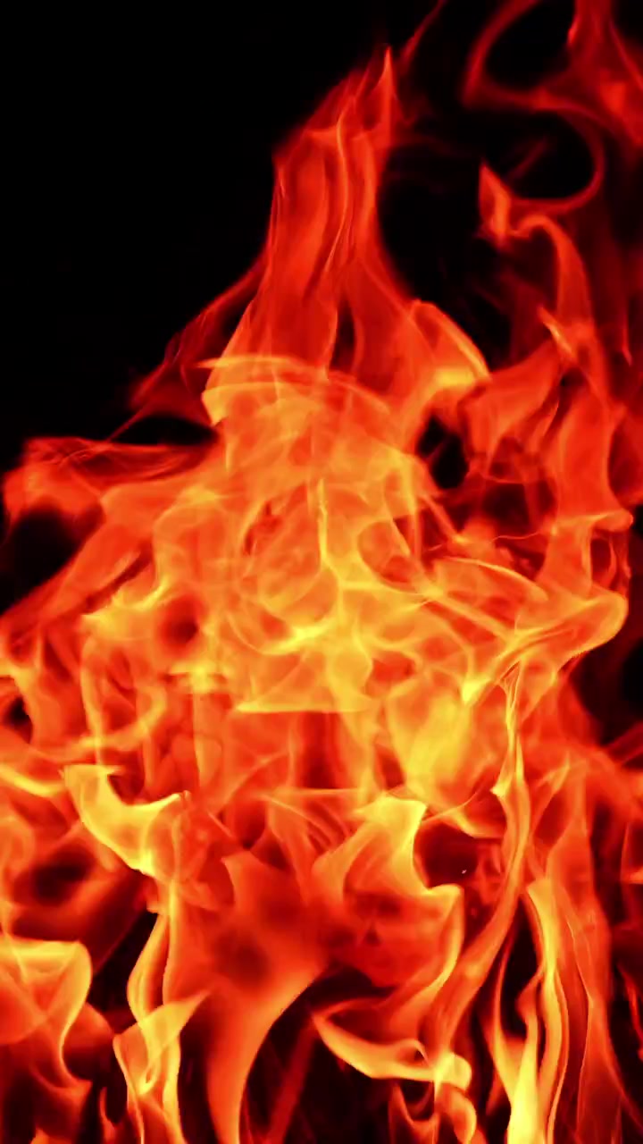 Dangerous fire with hot flames going up. Campfire at dark night. Close up. Vertical video