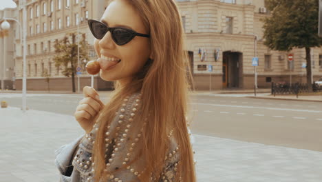 mujer comiendo piruleta en la ciudad