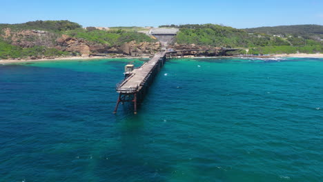 old abandoned pier on summer day, person jumping off pier into sea, aerial view