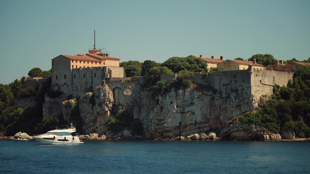 La storica fortezza Fort Royal si erge su una scogliera che domina il bellissimo mare Mediterraneo blu, con uno yacht che naviga sotto.