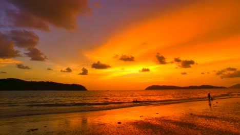 sunset with lots of colors on a tropical beach in langkawi with parachutes and an island in the background