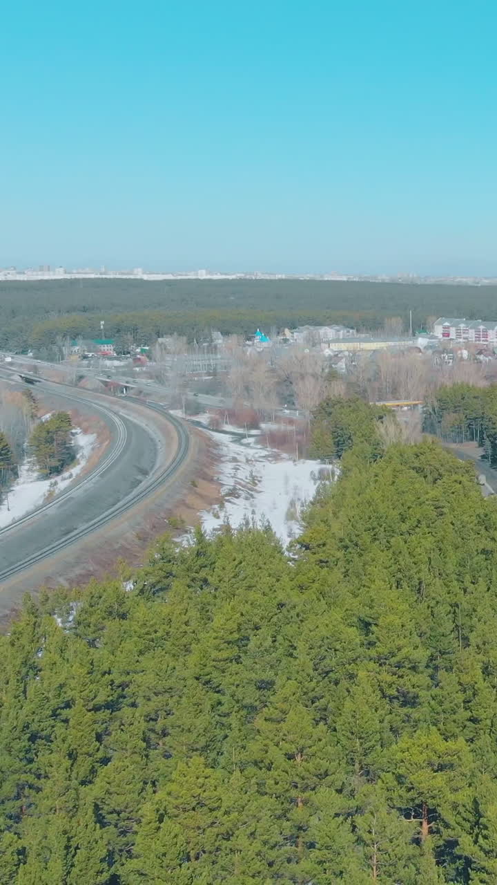 grey roads with white snow on roadside kerbs surrounded by pictorial green pine trees in spring upper view